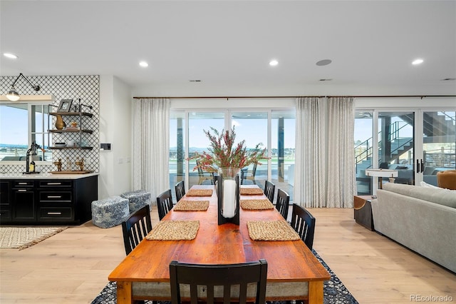 dining room featuring light hardwood / wood-style floors, a wealth of natural light, and a water view