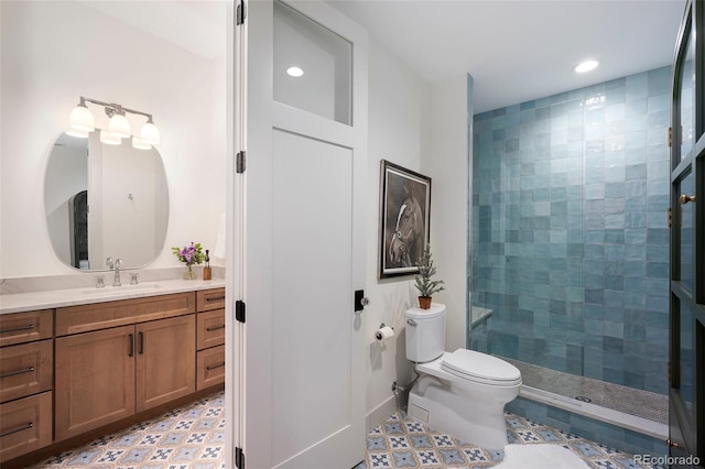 bathroom with tile patterned floors, vanity, a tile shower, and toilet