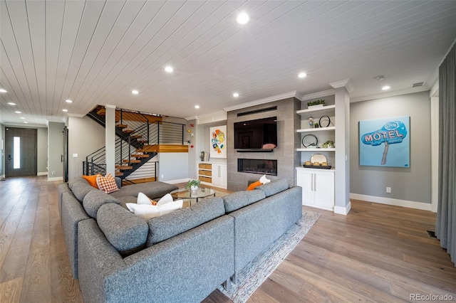 living area featuring a fireplace, wood finished floors, stairway, baseboards, and recessed lighting