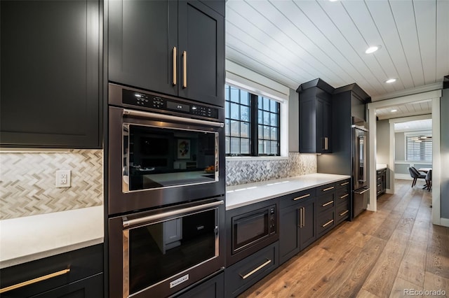 kitchen featuring light countertops, tasteful backsplash, built in microwave, and double oven