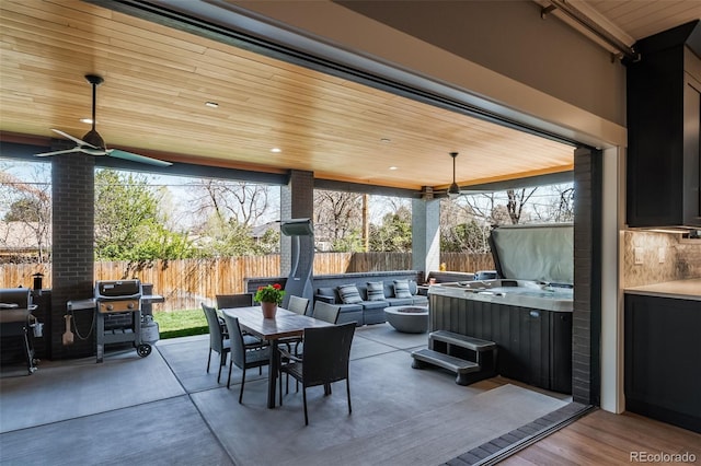 view of patio / terrace featuring a hot tub, grilling area, a fenced backyard, and outdoor dining space