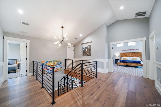 corridor featuring visible vents, wood finished floors, and an upstairs landing