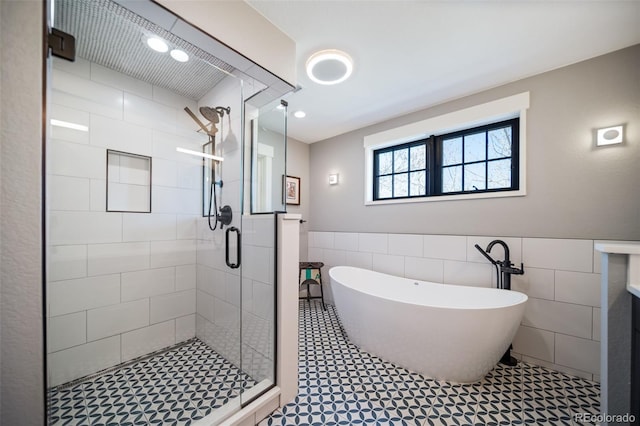 bathroom featuring a freestanding tub, tile walls, wainscoting, and a stall shower