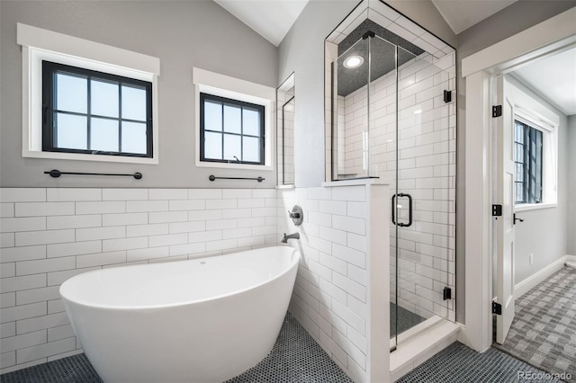bathroom with a freestanding bath, a stall shower, a wealth of natural light, and tile walls