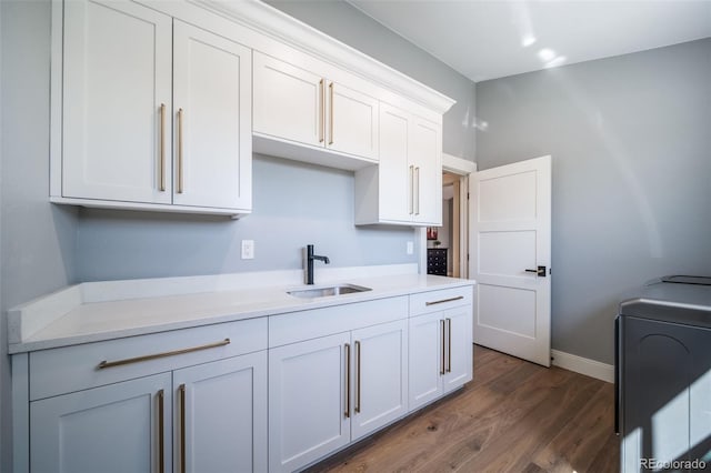 kitchen with baseboards, dark wood-type flooring, light countertops, white cabinetry, and a sink