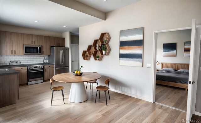 1643 Boulder St Unit 211, Denver, CO 80211 - kitchen with stainless steel appliances, dark countertops, tasteful backsplash, baseboards, and light wood-style flooring
