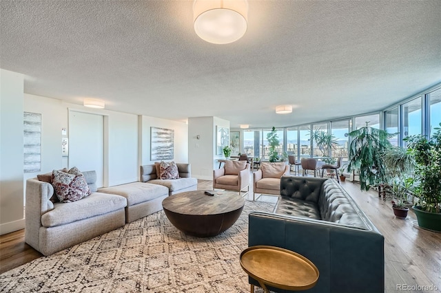 living room with a wealth of natural light, a textured ceiling, expansive windows, and wood finished floors