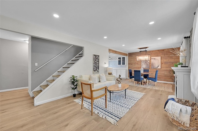 living area featuring light wood finished floors, wooden walls, recessed lighting, and stairs