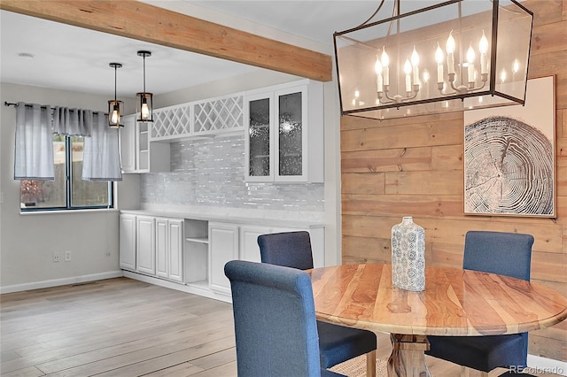 dining room featuring beam ceiling, baseboards, and light wood-style floors