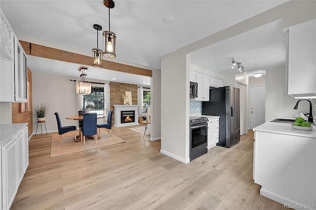 kitchen with light countertops, light wood-style flooring, stainless steel appliances, white cabinetry, and a sink