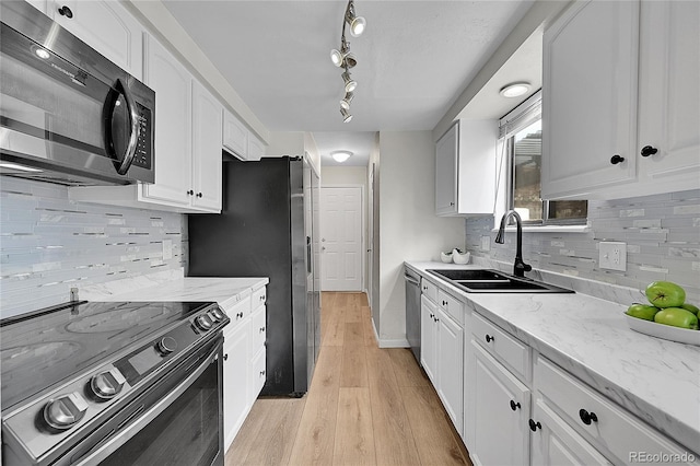 kitchen featuring light wood-style flooring, appliances with stainless steel finishes, white cabinetry, and a sink