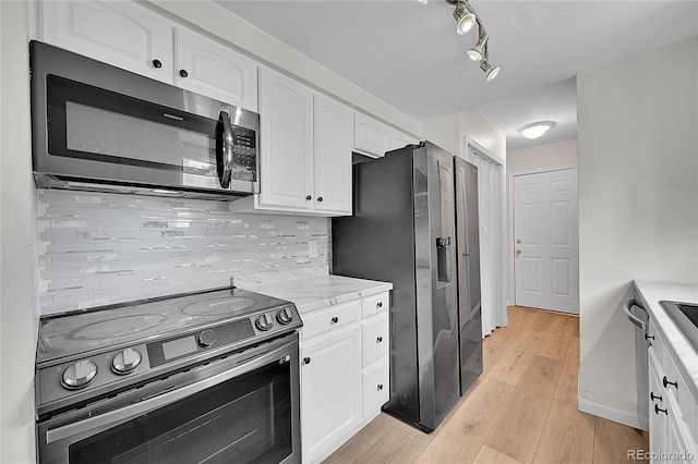 kitchen featuring light wood-type flooring, stainless steel appliances, decorative backsplash, and white cabinetry