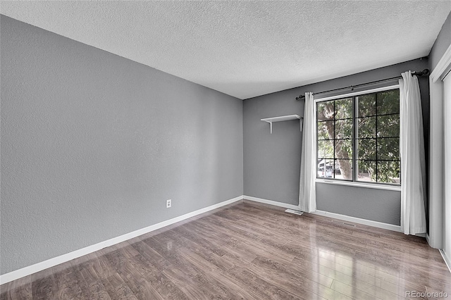 unfurnished room featuring baseboards, a textured ceiling, and wood finished floors