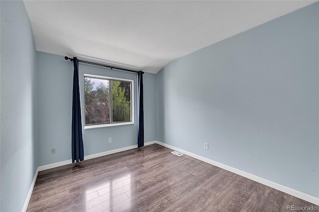 empty room with visible vents, baseboards, and wood finished floors