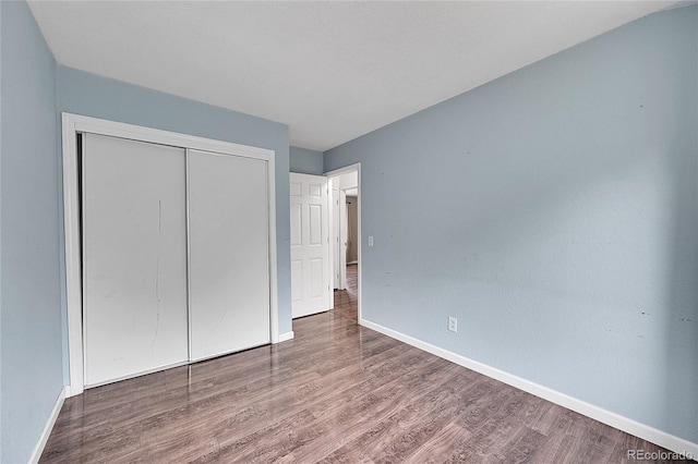 unfurnished bedroom featuring a closet, baseboards, and wood finished floors