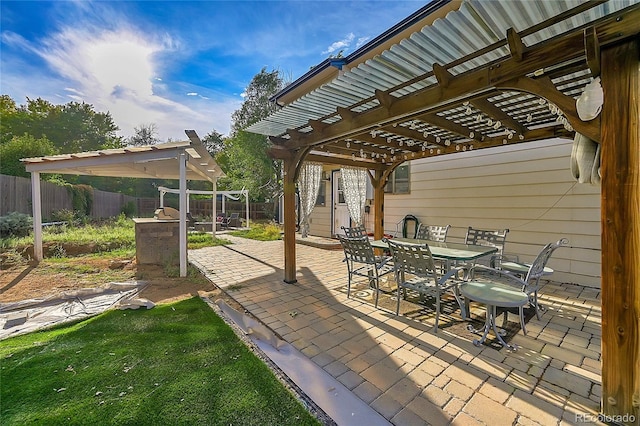 view of patio with outdoor dining space, fence, and a pergola