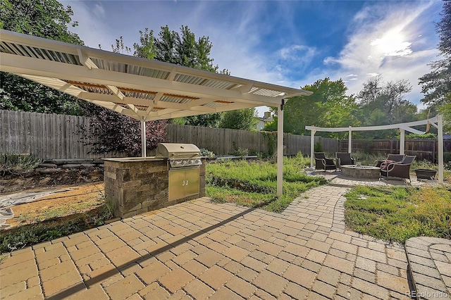 view of patio with area for grilling, a pergola, a fenced backyard, a fire pit, and an outdoor kitchen