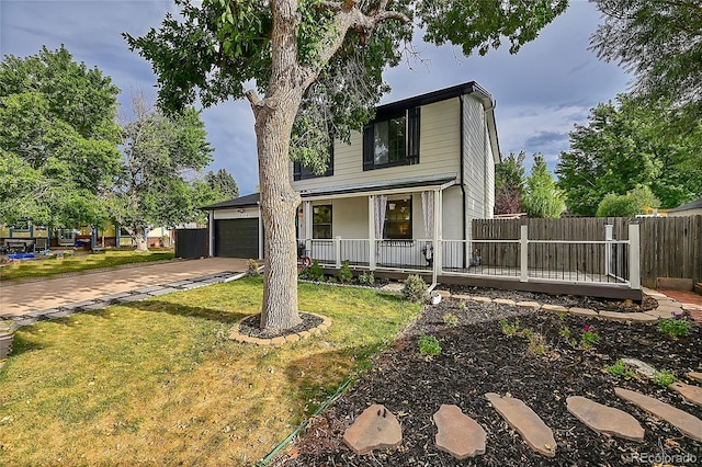 traditional-style house with a porch, fence, concrete driveway, an attached garage, and a front yard