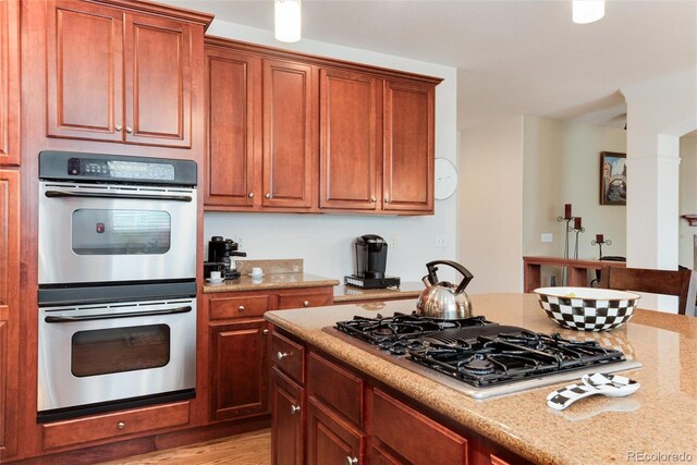 2959 W 110th Pl, Westminster, CO 80234 - kitchen featuring double oven, stovetop with downdraft, light stone countertops, light wood-style flooring, and brown cabinets