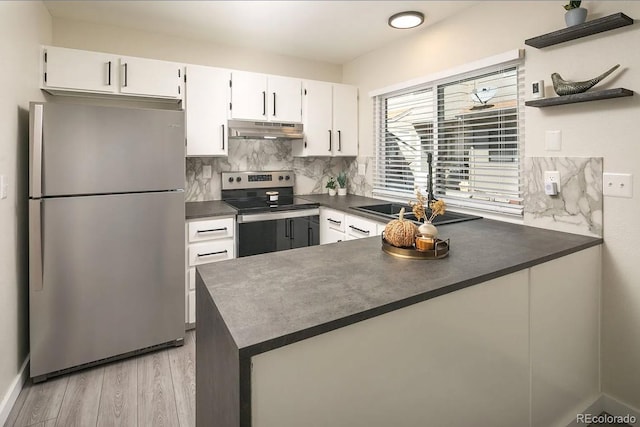 kitchen with stainless steel appliances, a peninsula, light wood-type flooring, dark countertops, and under cabinet range hood