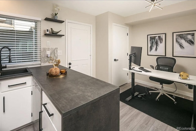 office area with light wood-type flooring and a sink