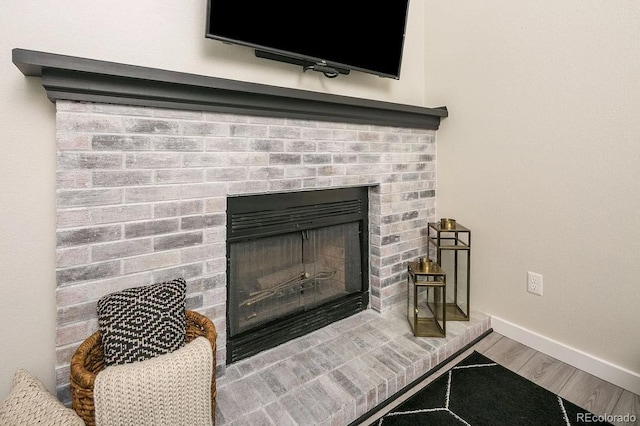 room details featuring baseboards, wood finished floors, and a brick fireplace