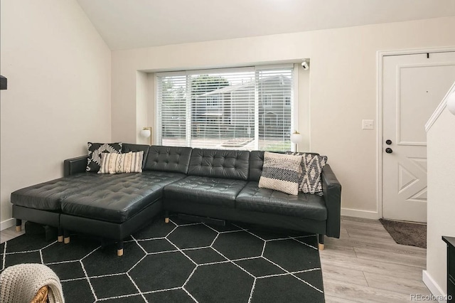 living room featuring wood finished floors, lofted ceiling, and baseboards