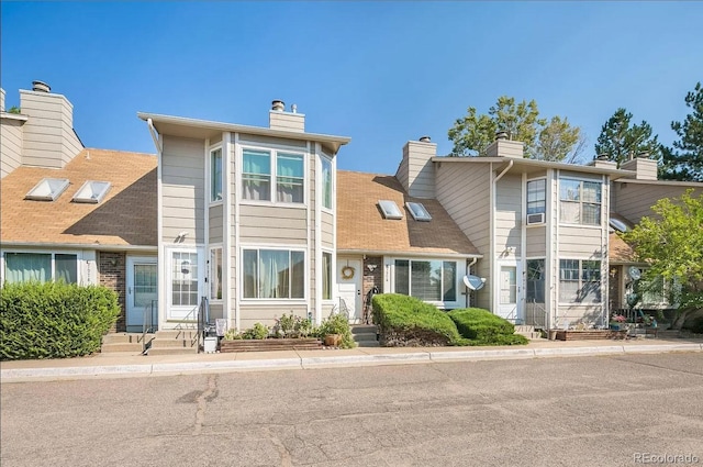 townhome / multi-family property with a chimney and entry steps