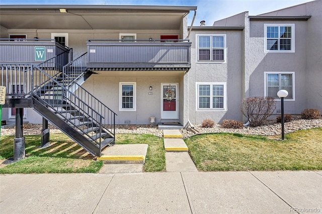 view of property with stucco siding, a front yard, and stairway