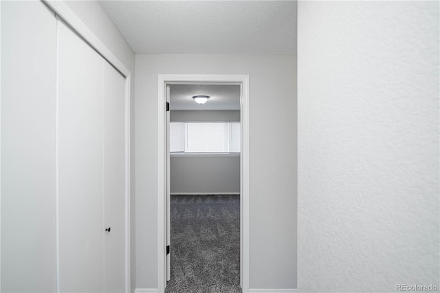 hallway with carpet flooring and a textured ceiling