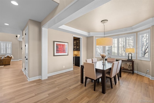 dining room with light wood-type flooring and a tray ceiling