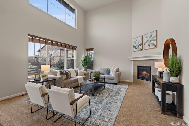 carpeted living room with a tile fireplace and a towering ceiling