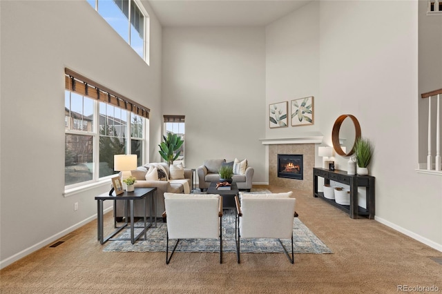 carpeted living room with a fireplace and a high ceiling