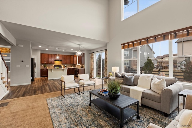 living room featuring dark colored carpet, a notable chandelier, and a high ceiling