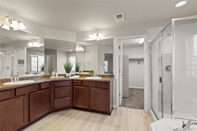 bathroom with hardwood / wood-style floors, vanity, a shower with door, and a chandelier