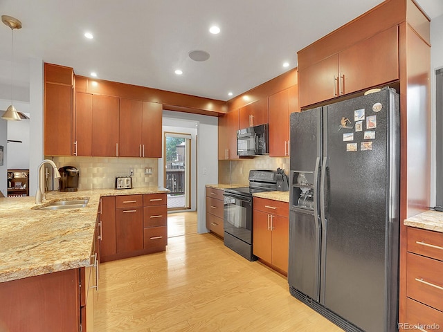 kitchen featuring light hardwood / wood-style flooring, pendant lighting, black appliances, backsplash, and sink