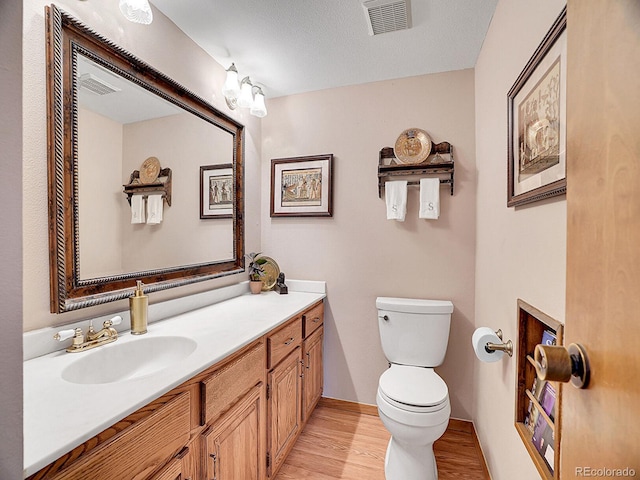 bathroom featuring toilet, wood-type flooring, vanity, and a textured ceiling