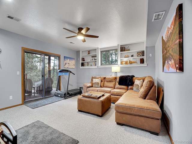 carpeted living room featuring a textured ceiling, ceiling fan, and built in features