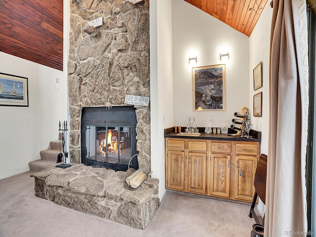 carpeted living room featuring high vaulted ceiling, indoor bar, wood ceiling, and a stone fireplace