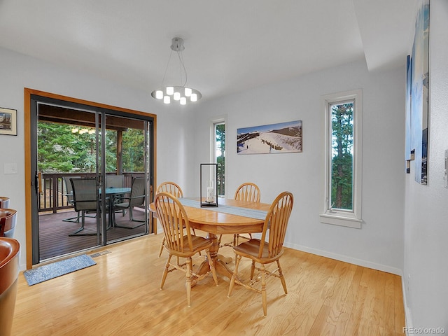 dining room featuring light wood-type flooring, a chandelier, and a healthy amount of sunlight