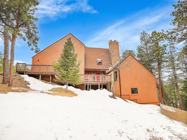 snow covered back of property with a wooden deck