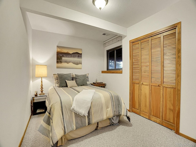 bedroom featuring a closet, a textured ceiling, and light colored carpet