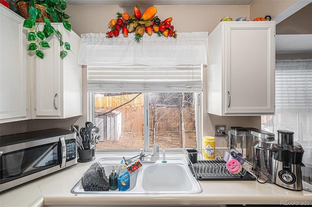 kitchen with light countertops, stainless steel microwave, and white cabinetry