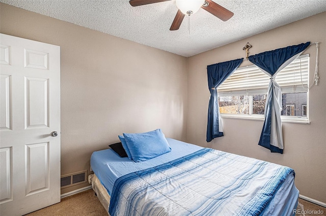 bedroom featuring visible vents, baseboards, a ceiling fan, carpet, and a textured ceiling