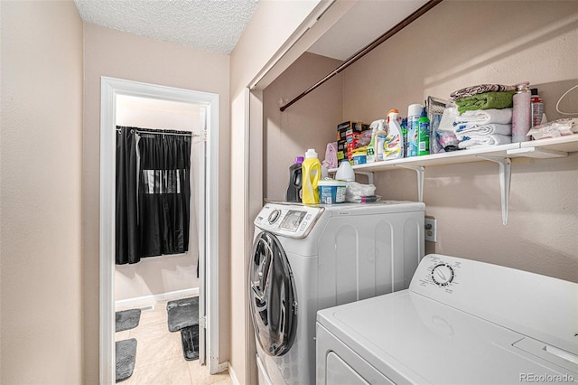 laundry area with laundry area, light tile patterned floors, a textured ceiling, and washing machine and clothes dryer