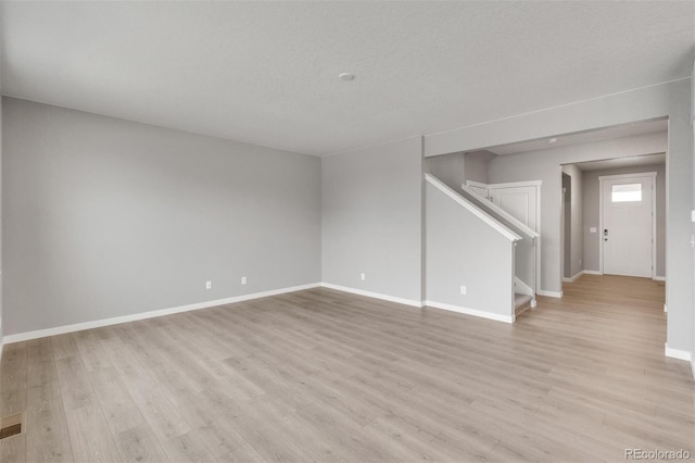 unfurnished living room with a textured ceiling and light hardwood / wood-style floors