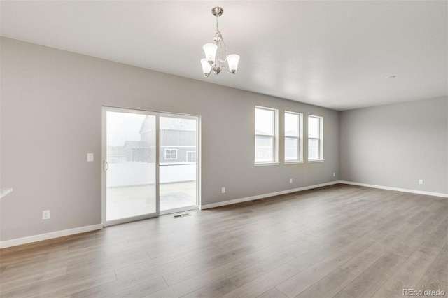 unfurnished room featuring light hardwood / wood-style floors and a chandelier