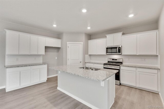 kitchen with an island with sink, sink, white cabinets, and stainless steel appliances