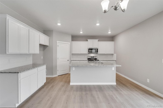 kitchen featuring light wood-type flooring, stainless steel appliances, white cabinetry, and a kitchen island with sink