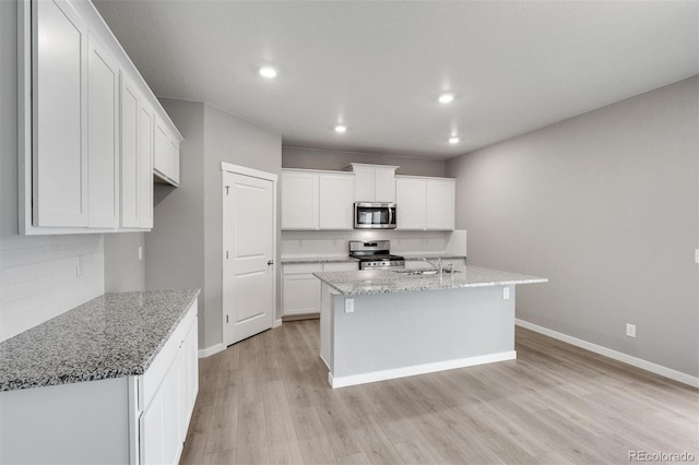 kitchen featuring white cabinetry, sink, stainless steel appliances, light hardwood / wood-style floors, and a kitchen island with sink